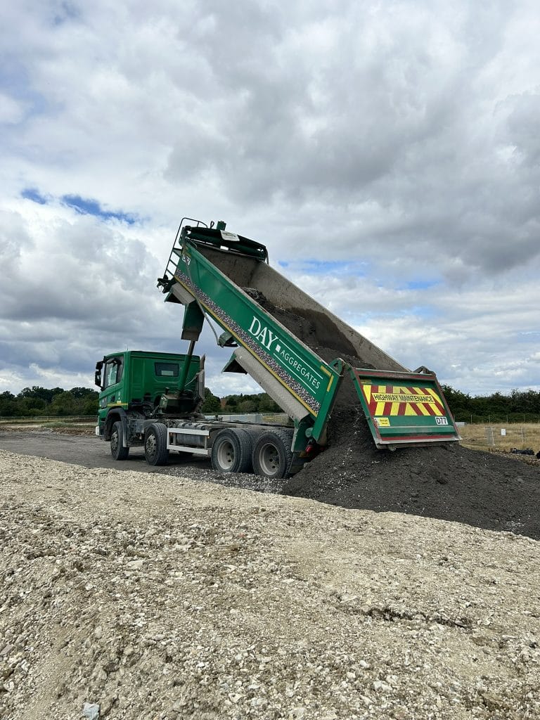 a truck loading gravel into a dirt area